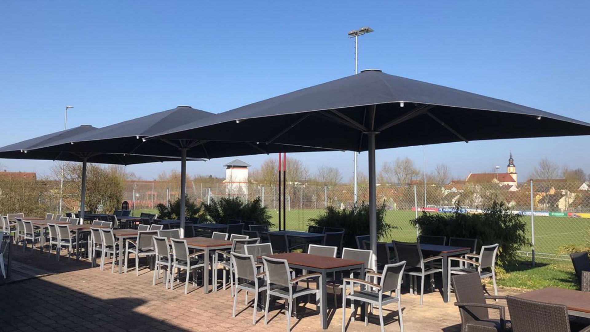 Dunkle Großschirme über einer Restaurantterrasse