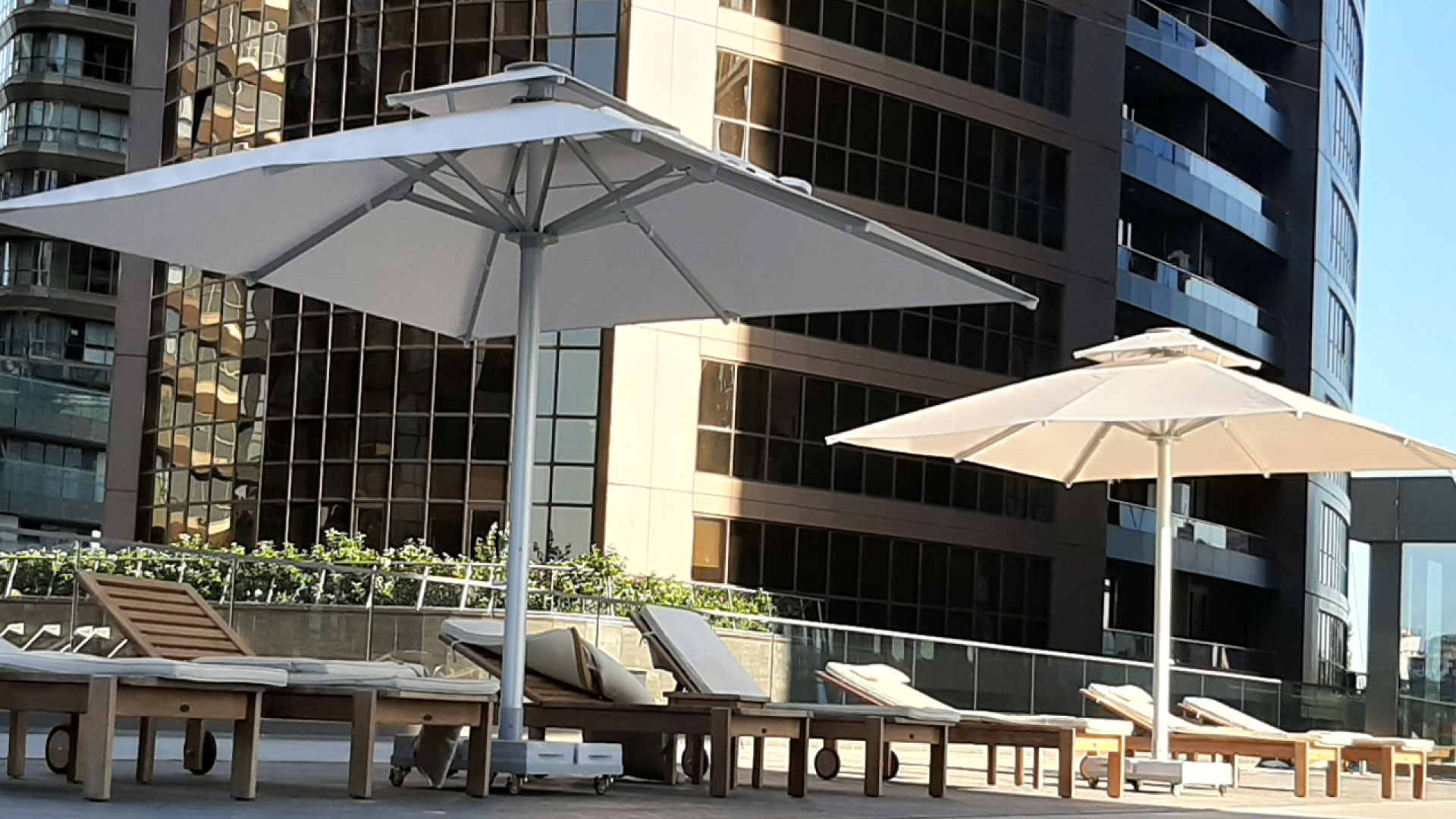 Sonnenschirme an einem Hotelpool vor einer Glasfassade