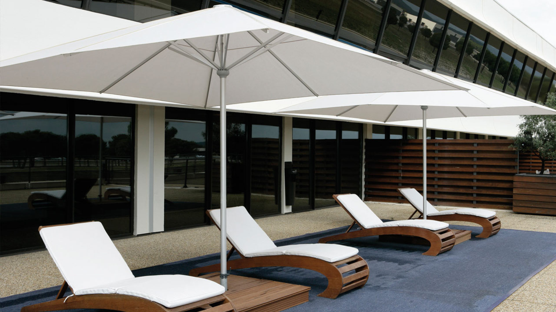 Weiße Premium-Sonnenschirme über Liegen auf einer Hotelterrasse