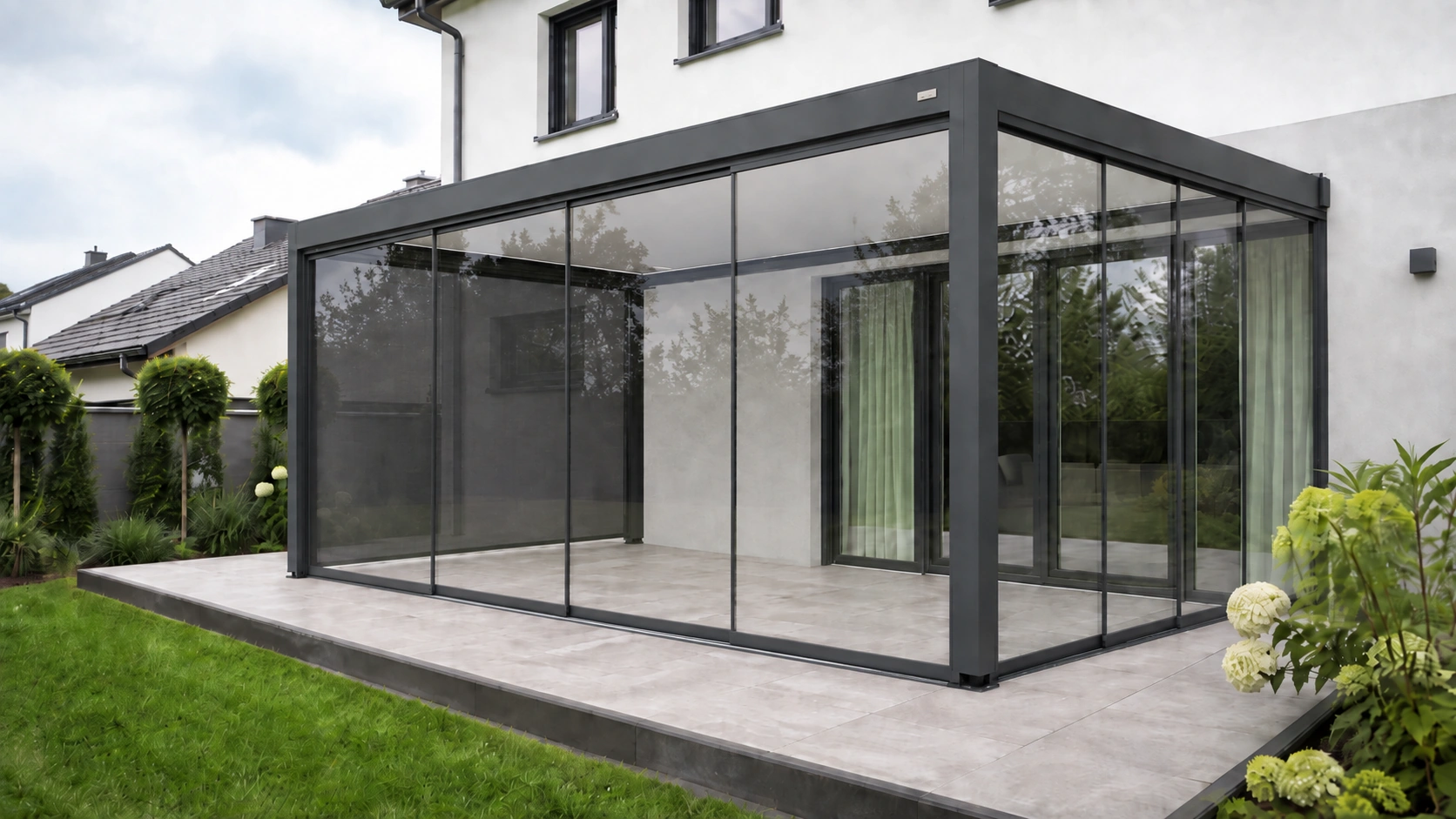 Hausterrasse mit anthrazitfarbener Lamellenpergola und seitlicher Glas-Schiebewand