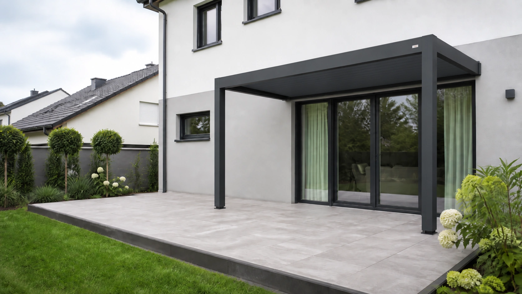 Hausterrasse mit wandmontierter anthrazitfarbener Lamellenpergola