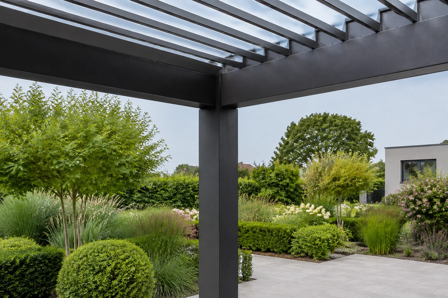 Eckpfosten und Lamellendach einer Pergola vor einem Garten