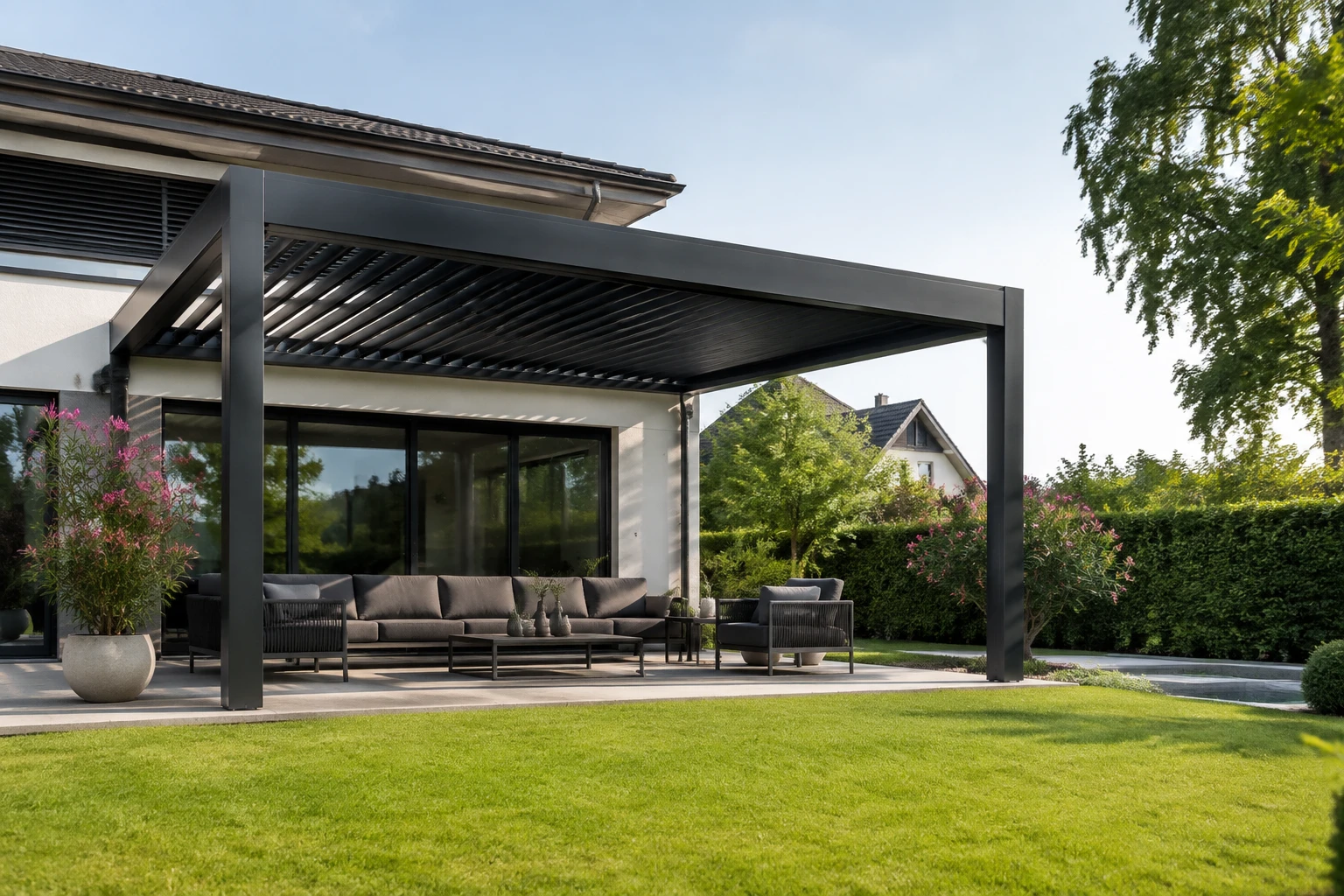 Anthrazitfarbene Pergola mit Lamellendach an einem Wohnhaus